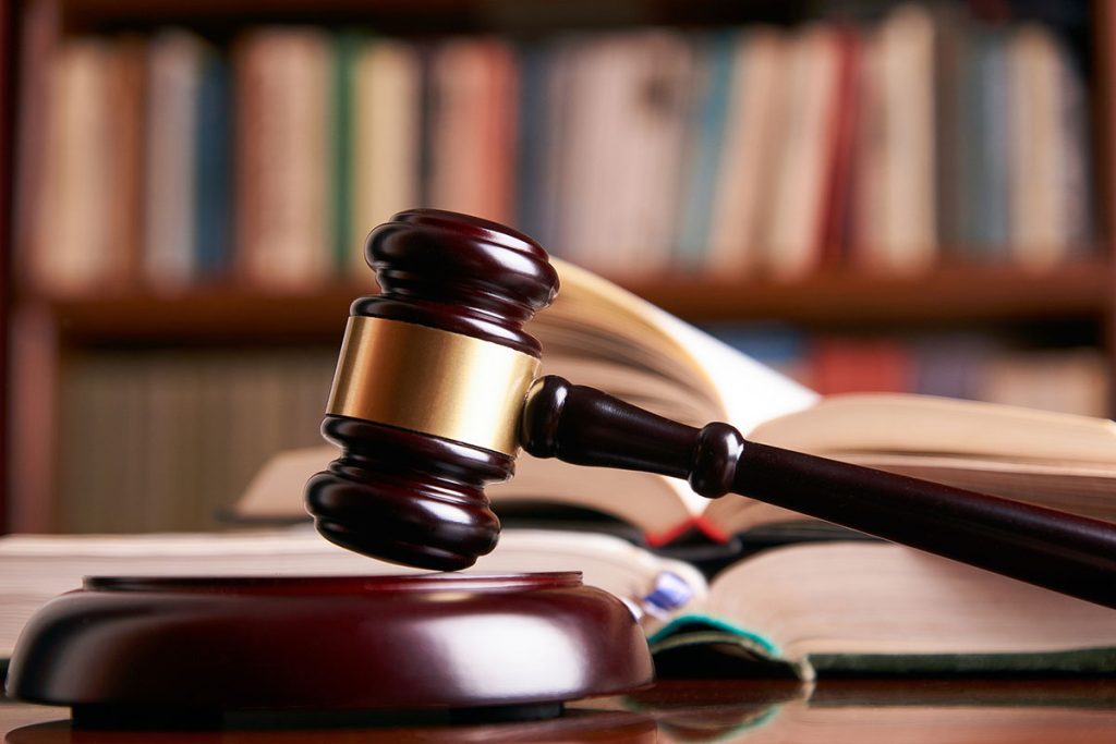 A wooden judge's gavel rests on an open legal book in a library, symbolizing personal injury law and legal services.