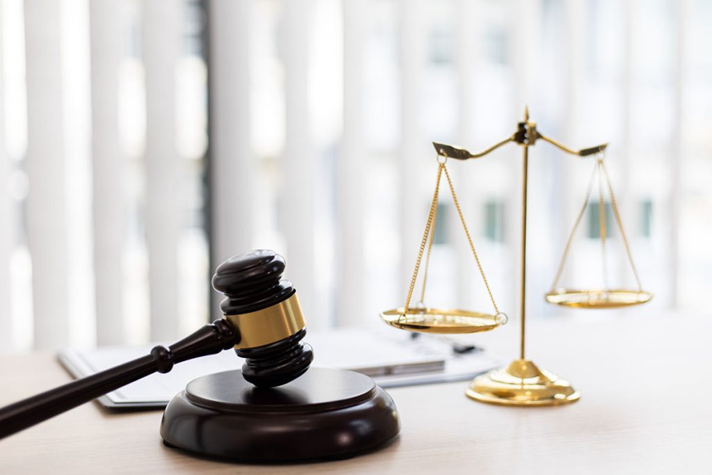A wooden gavel resting next to a golden scale of justice on a desk, representing legal insights from a personal injury law firm.