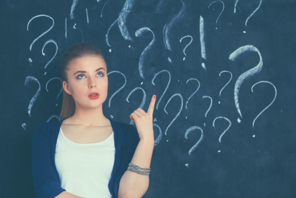woman pointing at question marks on chalkboard