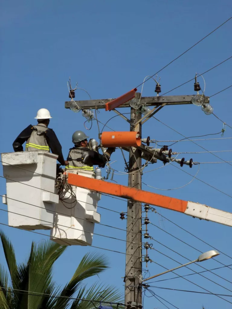 An electrical utility worker in a hard hat working on power lines, illustrating the risks and prevention of severe electrical injuries.