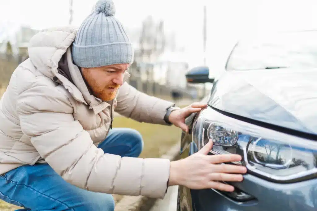 Man inspecting car headlight damage after a Texas car accident