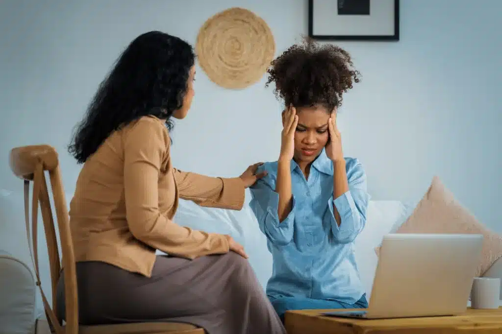 A woman sitting on a couch with her head in her hands, experiencing stress and psychological trauma from a car accident that can cause PTSD.
