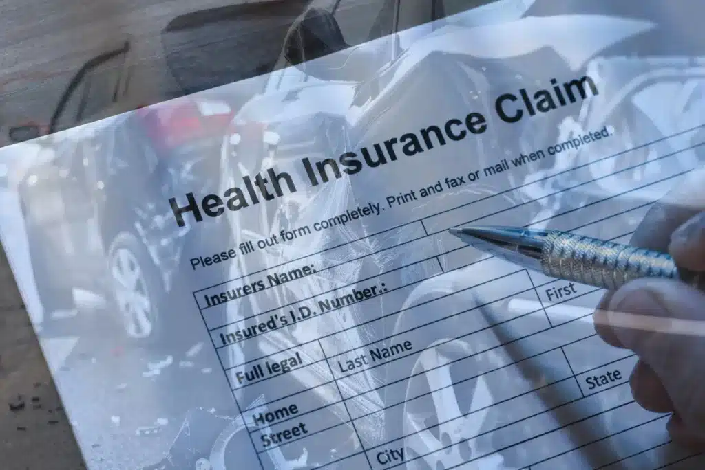 A person filling out a health insurance claim form after a Texas car accident.