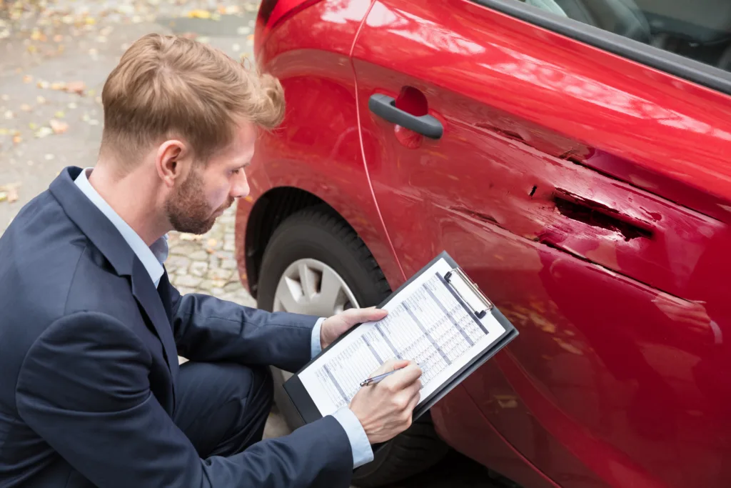 insurance agent inspecting sideswiped car damage