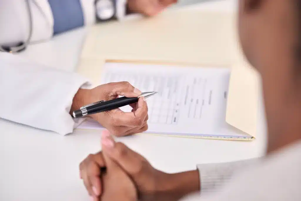 A doctor or medical professional holding a pen over a medical chart or workers' compensation claim form, representing a medical evaluation for an injury.
