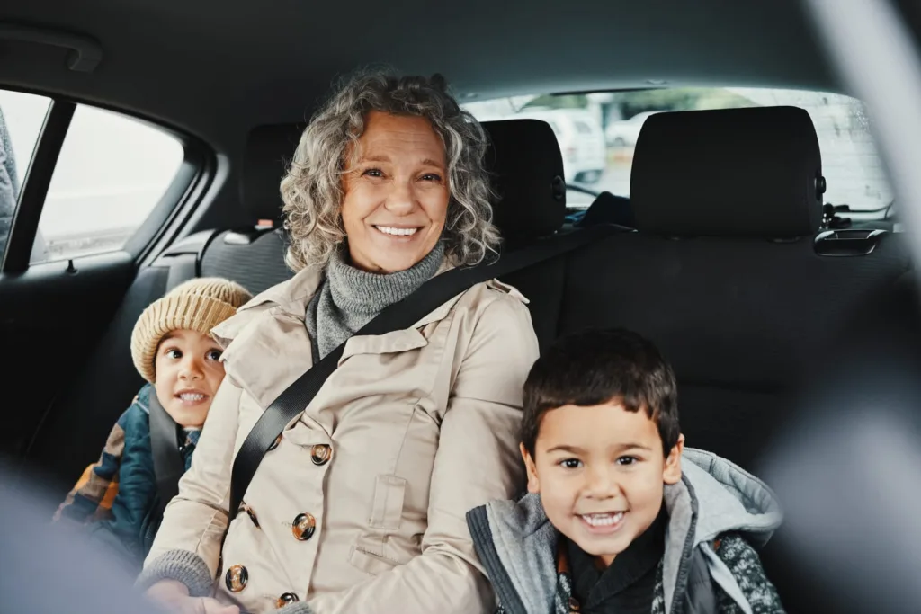 Elderly woman and two children riding in a car as rideshare passengers