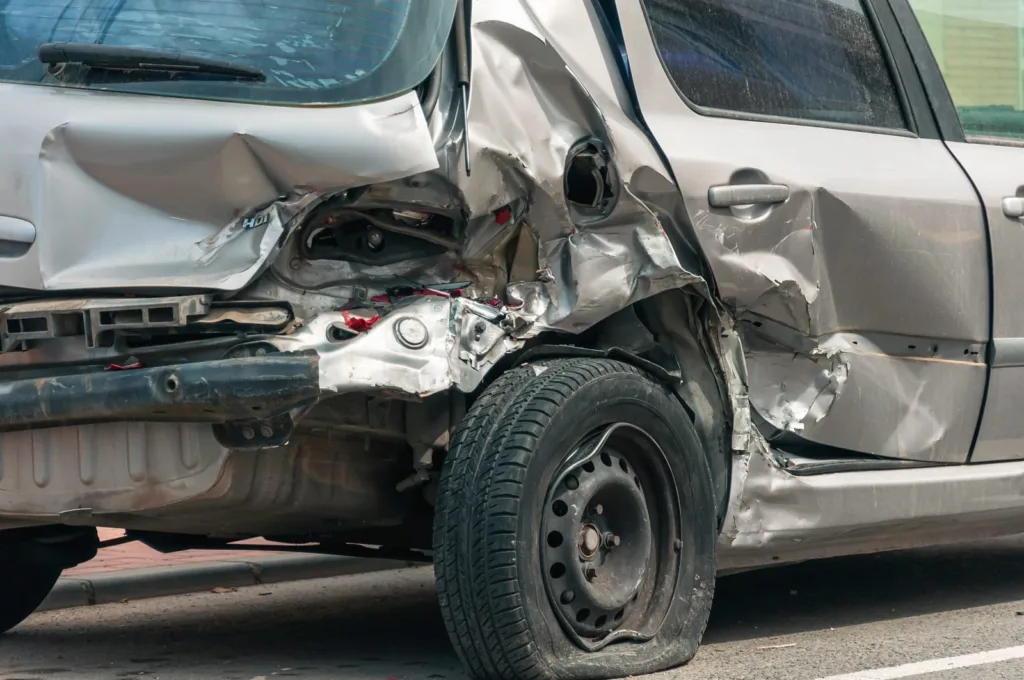 A silver car with extensive rear-end and side damage from a Florida car accident collision.