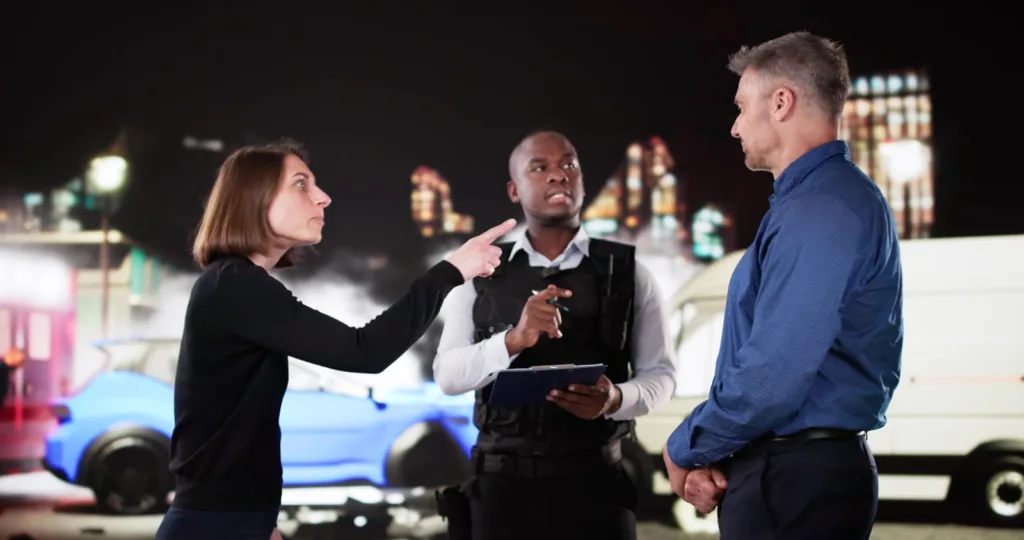 A woman pointing and talking with an officer and another driver after a car accident, representing the process of correcting errors in a police report.