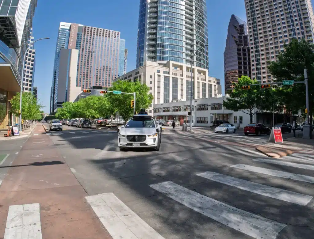 Waymo autonomous robotaxi driving through a downtown city intersection